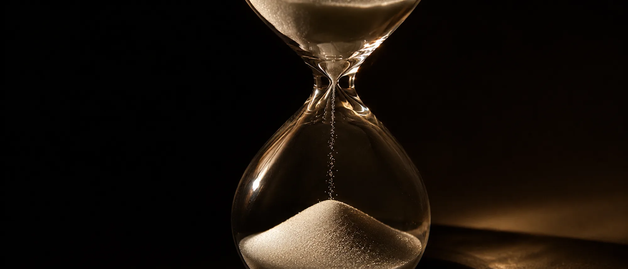 Hourglass in warm light, sand still high in the upper bulb